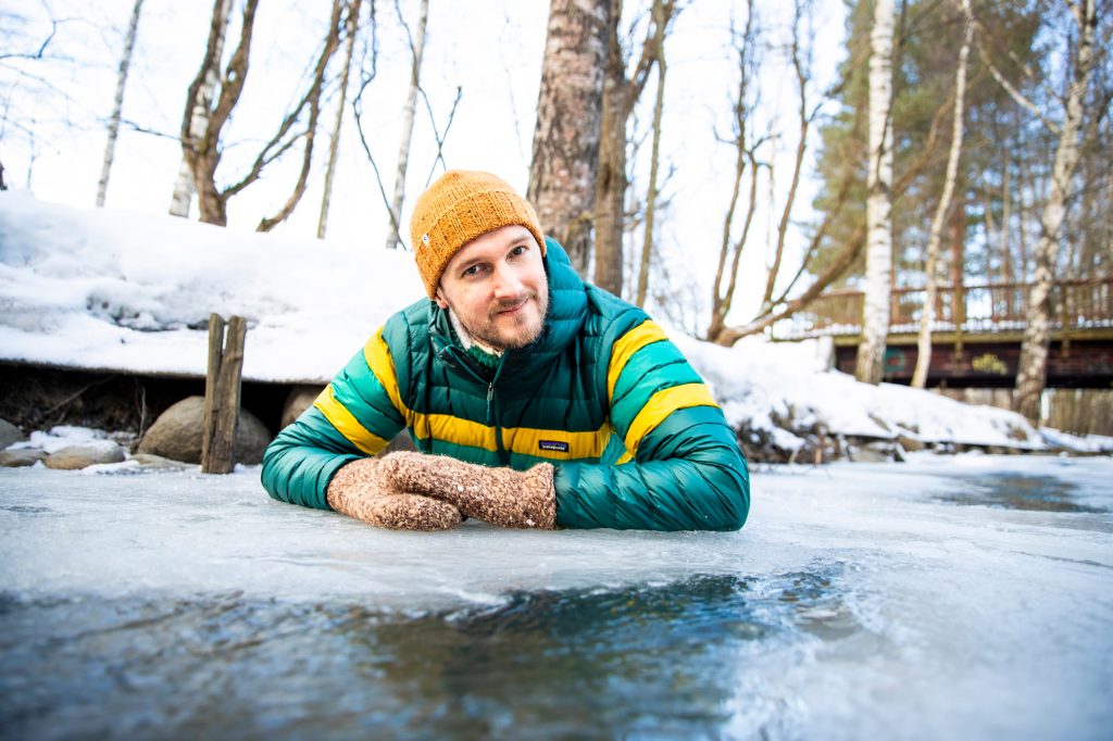 Keltapipoinen Pekko-Joonas Rantamäki makoilee jäällä kyynärpäidensä varassa, kintaat kädessä. Ympäristö näyttää talviselta puromaisemalta, takana siintää puinen kävelysilta. Poserataanko kuvaajalle artikkelissa mainitun Vantaanjoen varressa?
